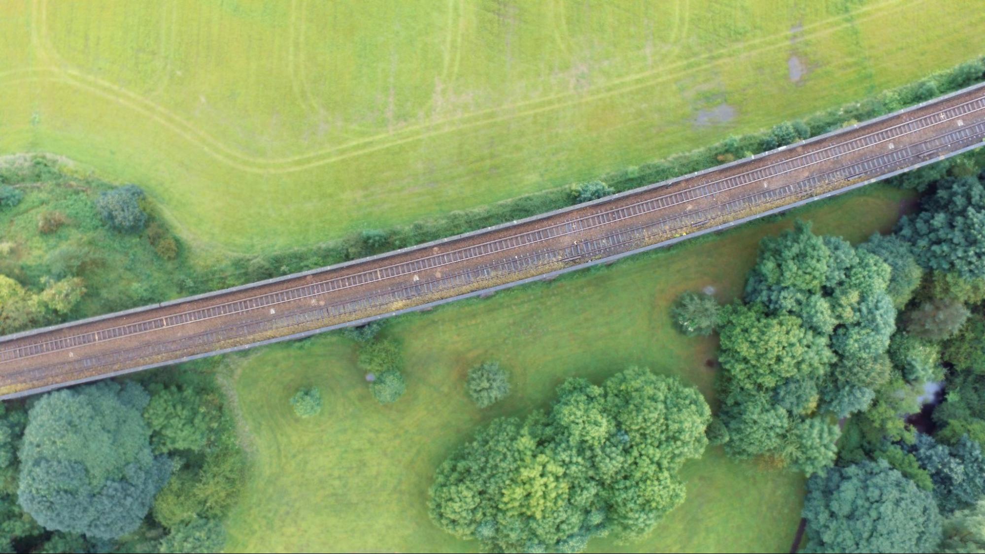 An aerial view of railroad tracks cutting through a green landscape